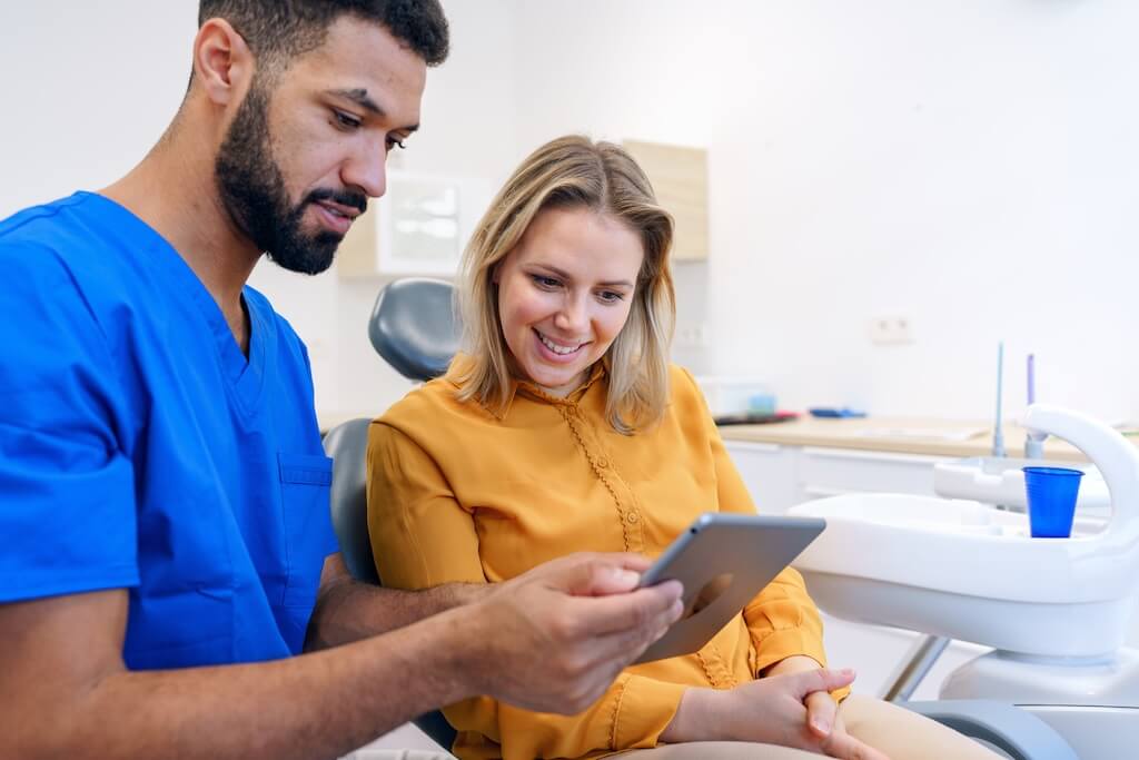 A dental professional showing a patient a digital treatment preview